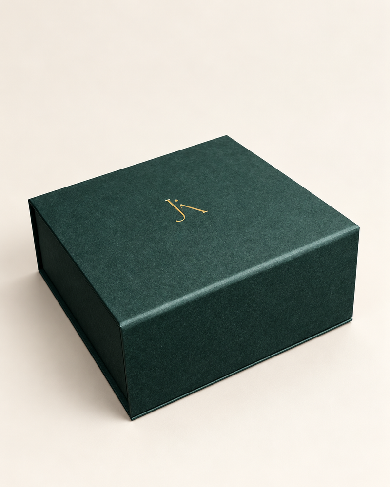 Closed deep green Jade Aura gift box with a gold monogram